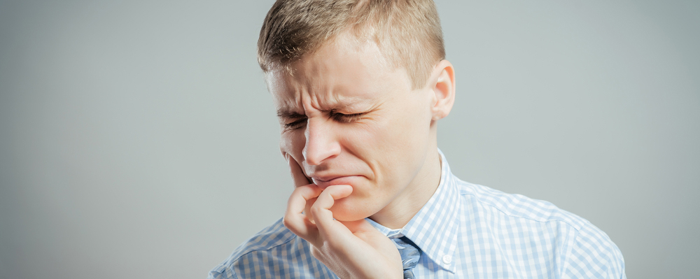 Man holding sore mouth
